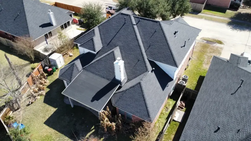 Drone photo of a complex multi-gable asphalt shingle roof on a brick home in a Cypress, TX neighborhood