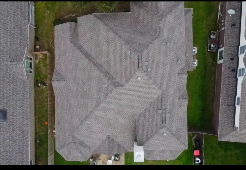 Straight-down aerial view of a gray asphalt shingle roof with multiple hips and valleys on a Cypress home