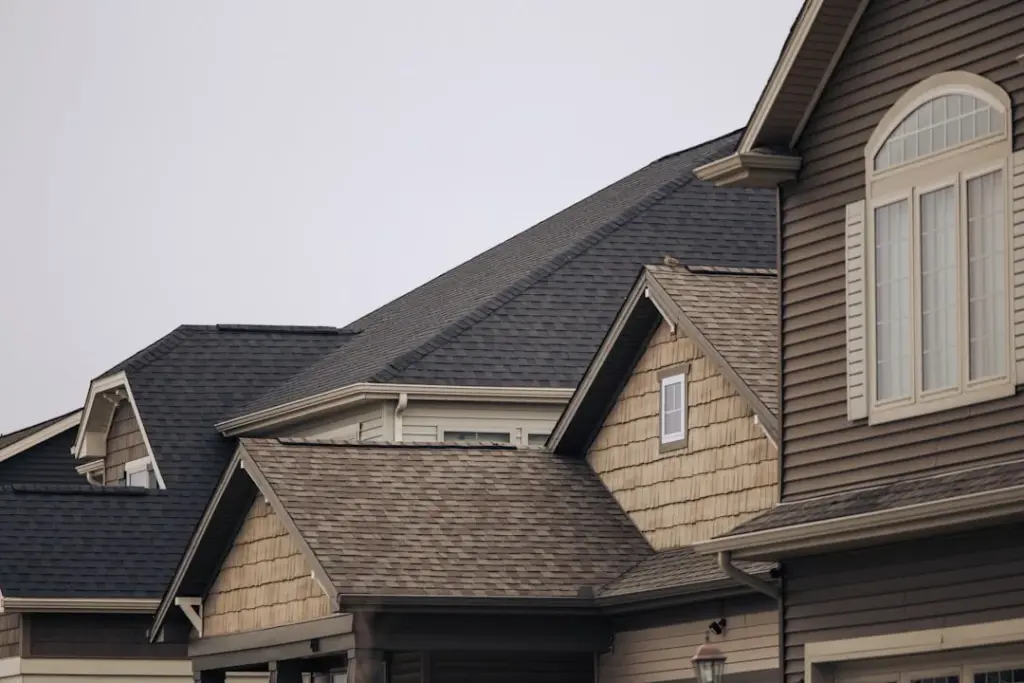 Two-story house with multiple gables, shake siding accents, and asphalt shingle roofing in Cypress, TX